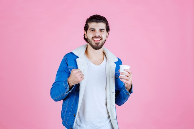 Mann mit einer Kaffeetasse, die seine Faust demonstriert