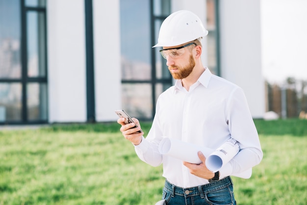 Mann mit Entwürfen unter Verwendung des Smartphone