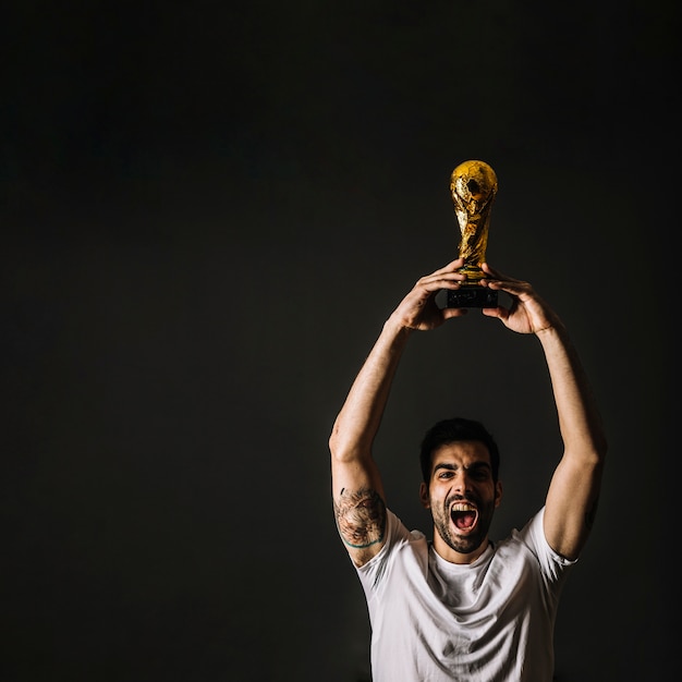 Mann mit FIFA-Trophäe feiert Sieg
