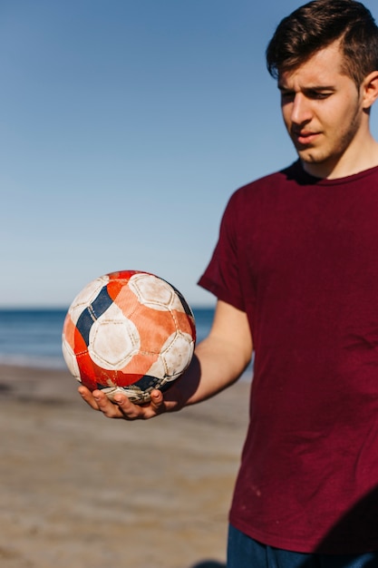 Kostenloses Foto mann mit fußball am strand