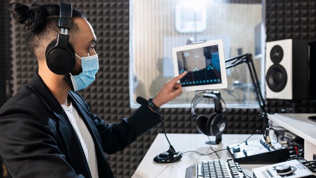 Mann mit Gesichtsmaske, die an einem Radiosender arbeitet