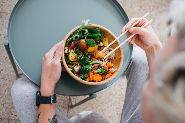 Mann mit gesundem Lebensstil und grüner Lebensmittelauswahl isst frisches und köstliches Buddha-Schüsselgericht mit Nährstoffen und Proteinen