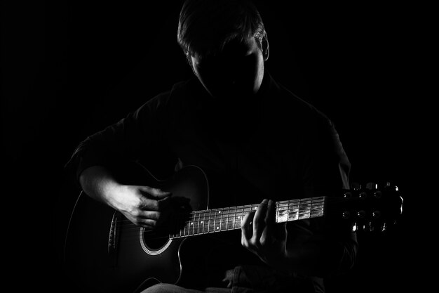 Mann mit Gitarre in der Dunkelheit