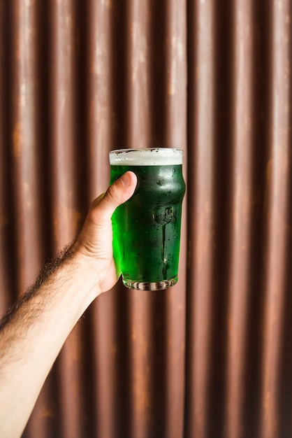 Mann mit Glas grünes Getränk nahe hölzerner Wand