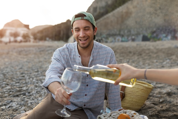 Mann mit Glas Wein während einer Strandparty