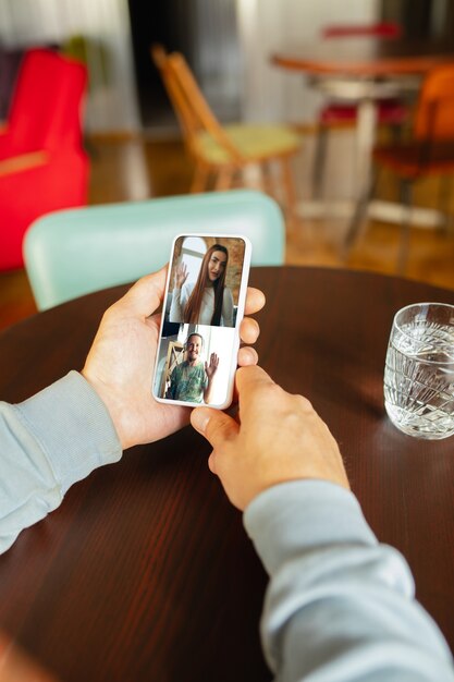 Mann mit Handy für Videoanruf beim Trinken von Wasser