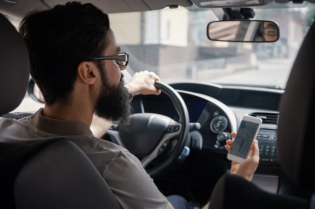 Mann mit Handy während der Fahrt.