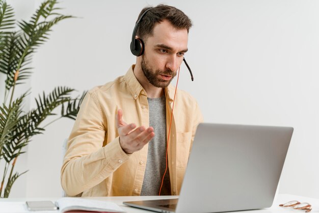 Mann mit Headset, der Videoanruf auf Laptop hat