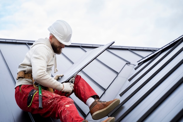 Mann mit Helm, der am Dach arbeitet, volle Aufnahme