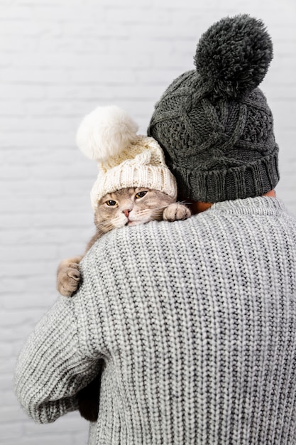 Mann mit hinterer haltener Katze mit Pelzmütze