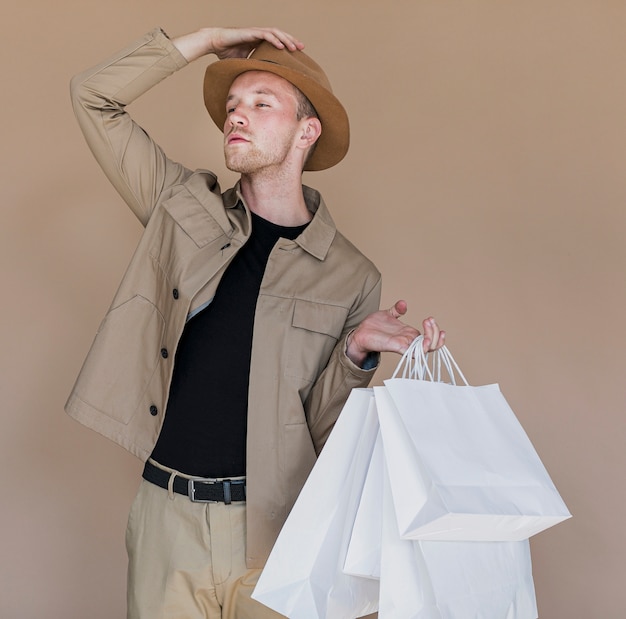 Mann mit Hut und Einkaufstaschen auf braunem Hintergrund