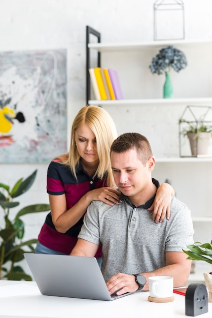 Mann mit ihrer Frau, die an Laptop arbeitet