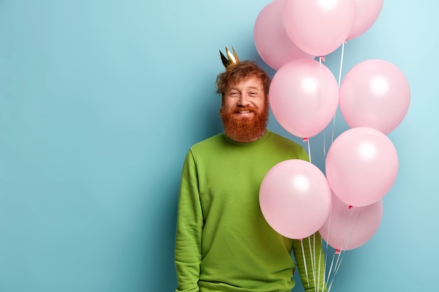 Kostenloses Foto mann mit ingwerbart, der luftballons hält