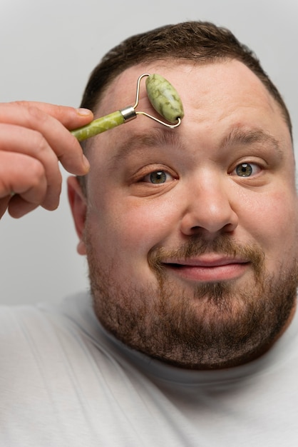 Kostenloses Foto mann mit jade-roller auf seinem gesicht für die hautpflege