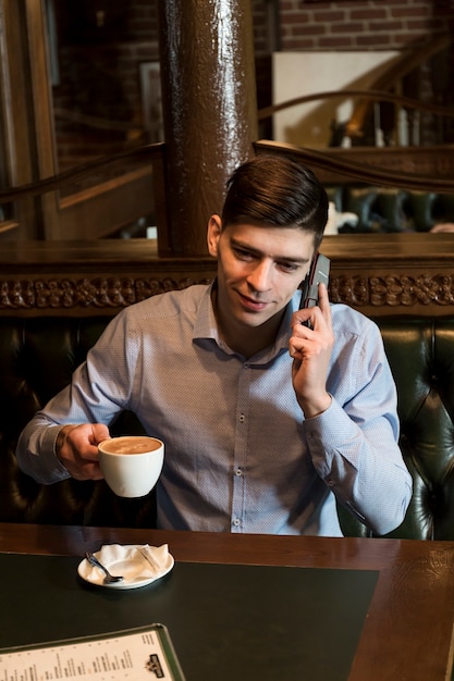 Mann mit Kaffee am Telefon sprechen