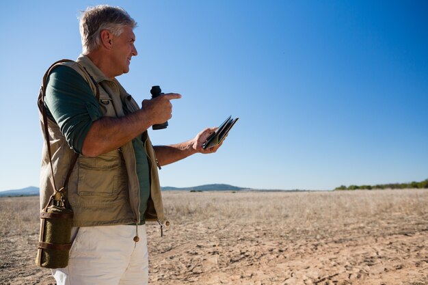 Mann mit Karte und Fernglas, die weg auf Landschaft schauen