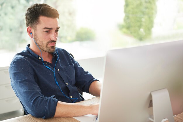 Mann mit Kopfhörern, die am Computer arbeiten