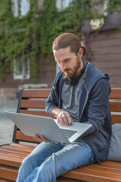 Mann mit Kopfhörern in der Stadt, die am Laptop arbeitet