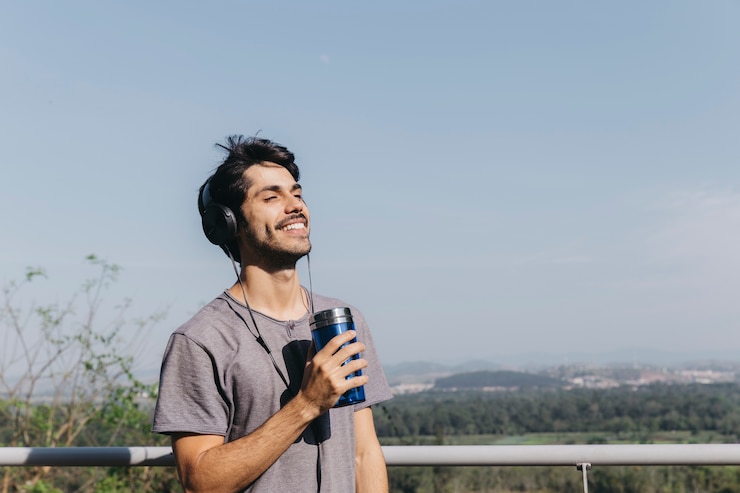 Kostenlose Foto mann mit kopfhörern und thermocup