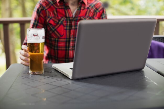 Mann mit Laptop mit Glas Bier auf Tisch