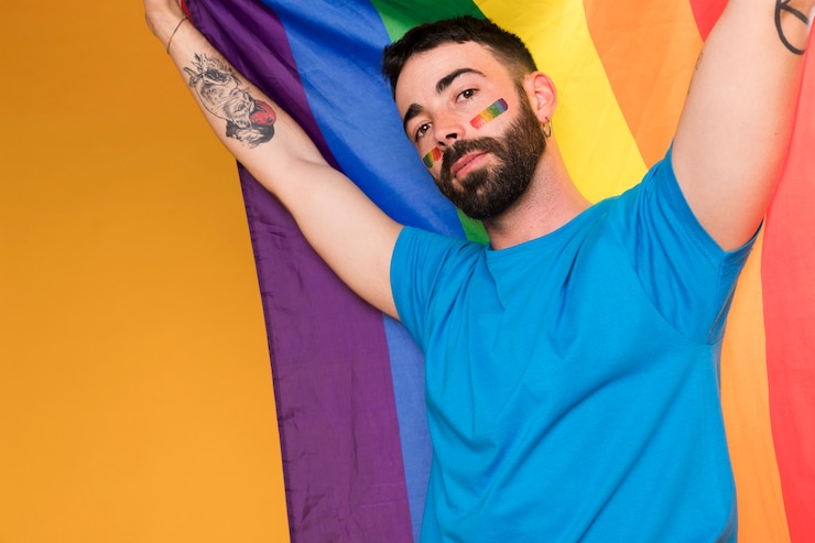 Kostenlose Foto mann mit lgbt-regenbogen auf gesicht mit mehrfarbiger flagge