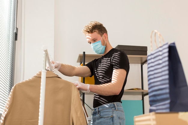 Mann mit Maske, die Kleidung betrachtet