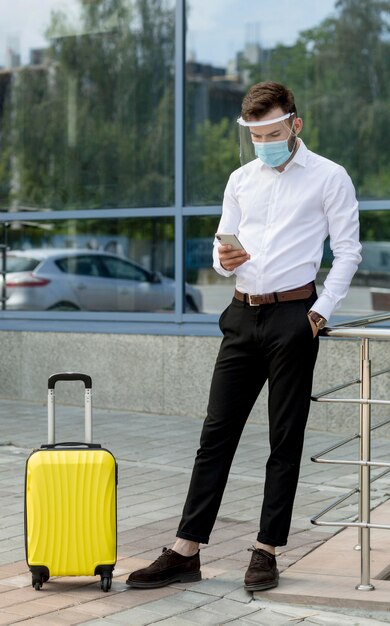 Mann mit Maske und Gepäck mit Handy