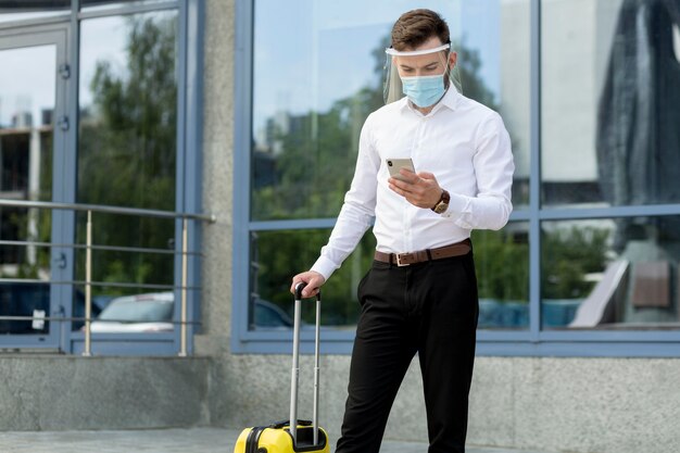 Mann mit Maske und Gepäckkontrolltelefon