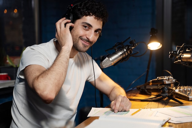 Mann mit Mikrofon und Kopfhörern, der einen Podcast im Studio laufen lässt