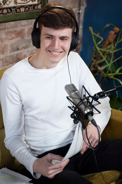 Mann mit Mikrofon und Kopfhörern, der einen Podcast im Studio laufen lässt