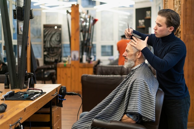 Kostenloses Foto mann mit mittlerem schuss bekommt haarschnitt