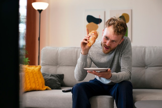 Kostenloses Foto mann mit mittlerem schuss, der croissant isst