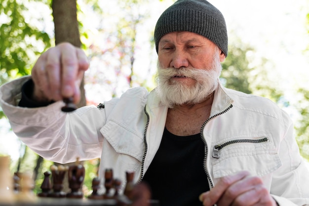 Kostenloses Foto mann mit mittlerem schuss, der draußen schach spielt