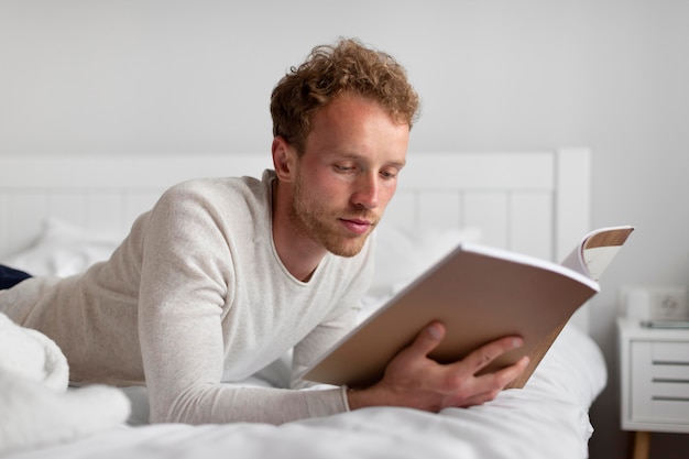 Mann mit mittlerem Schuss, der im Bett liest