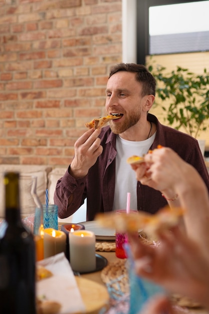 Kostenloses Foto mann mit mittlerem schuss, der pizza isst