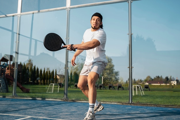 Mann mit niedrigem Winkel, der Paddle-Tennis spielt