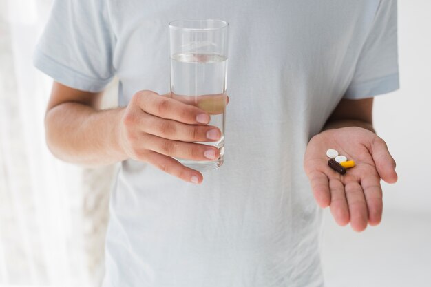 Mann mit Pillen und Wasser in den Händen