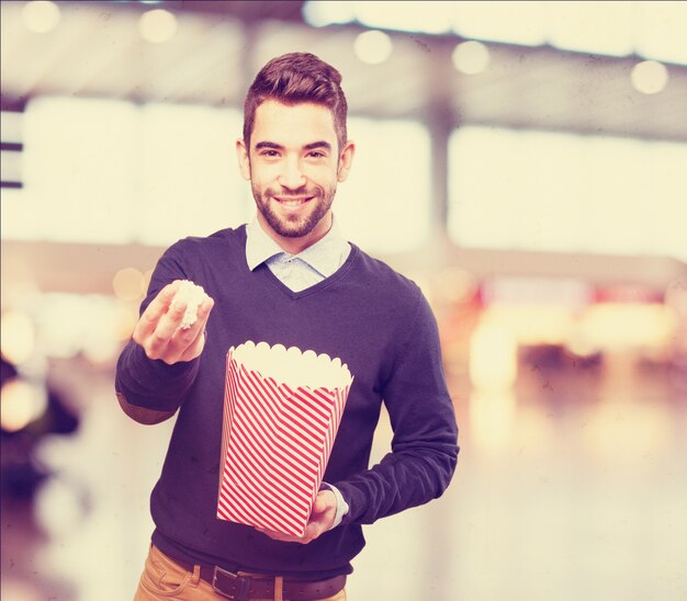 Mann mit Popcorn in der einen Hand und einem Paket in der anderen