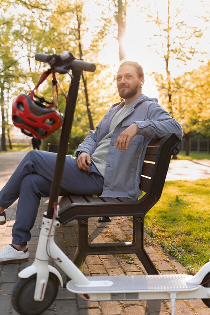 Mann mit Roller sitzt auf einer Bank