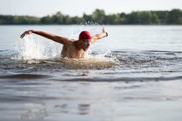 Mann mit roter Kappe, die im See schwimmt