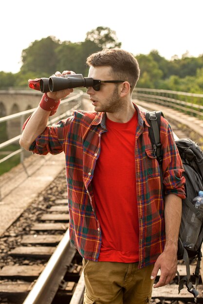 Mann mit Rucksack, der mit Fernglas in die Ferne schaut