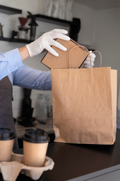 Mann mit Schürze bereitet Essen zum Mitnehmen vor