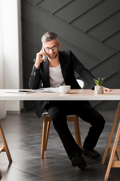 Mann mit schwarzer jacke zuhause sprechend am telefon