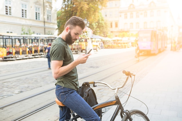 Kostenloses Foto mann mit seinem fahrrad unter verwendung des smartphone