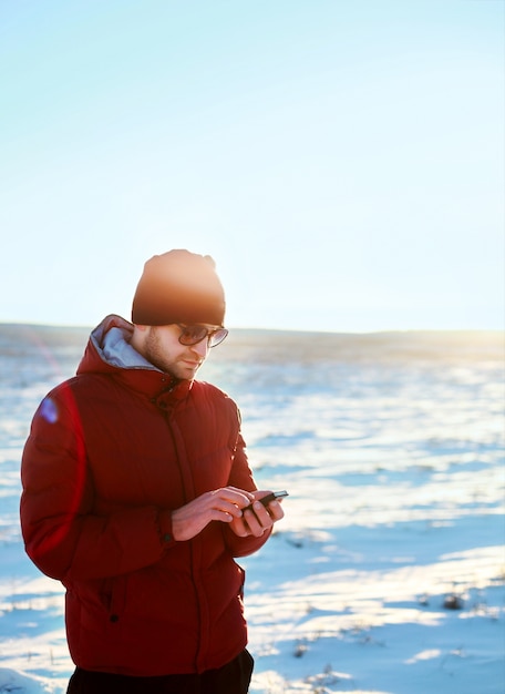 Mann mit seinem Handy in der schneebedeckten Feld