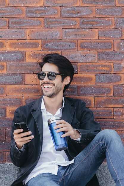 Mann mit Smartphone und Schale nahe Wand