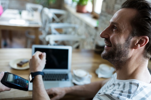 Kostenloses Foto mann mit smartwatch für express-pay in coffee-shop