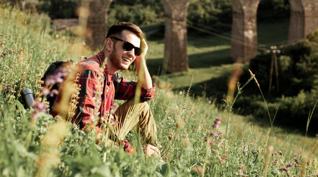 Mann mit Sonnenbrille, die im grünen Feld sitzt