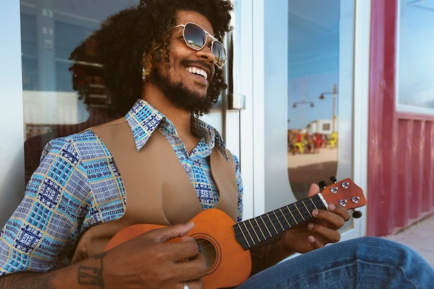 Mann mit Sonnenbrille posiert im Retro-Stil mit Ukulele