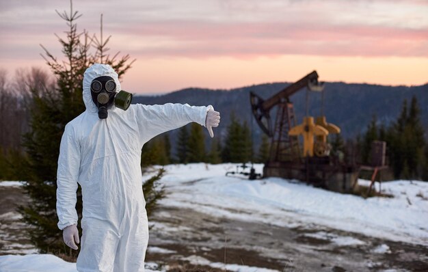 Mann mit weißem Overall und Gasmaske in einem Ölfeld neben dem Ölpumpenheber